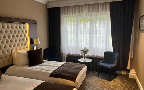 a hotel room with two beds and a window at Warren House Hotel in Kingston upon Thames