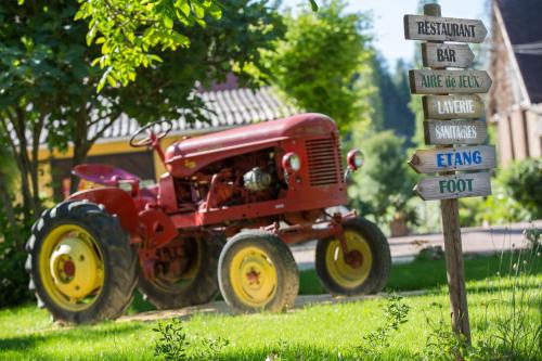 un trattore rosso seduto accanto a un cartello stradale di Camping La Ferme de Perdigat a Limeuil