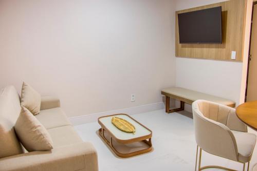 a living room with a couch and a table and a tv at Ramada Hotel & Suites Campos Pelinca in Campos dos Goytacazes