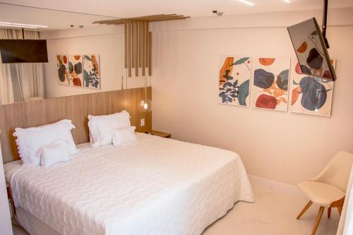 a bedroom with a white bed and some paintings at Ramada Hotel & Suites Campos Pelinca in Campos dos Goytacazes