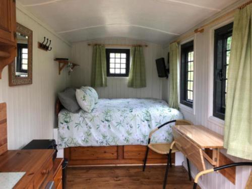 a bedroom with a bed in a tiny house at Snug & Secluded Lakeside Shepherds Hut 'Carp' in Uckfield