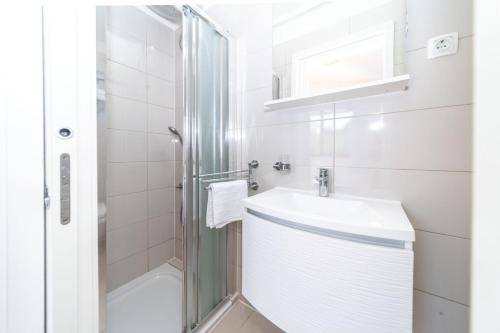 a white bathroom with a sink and a shower at Apartments Pende 3122 in Banjol