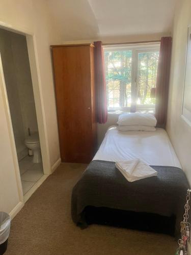 a bedroom with a bed and a window and a toilet at The Admirals Inn Guest House in Bracknell