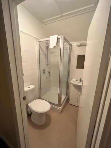 a bathroom with a toilet and a glass shower at The Admirals Inn Guest House in Bracknell
