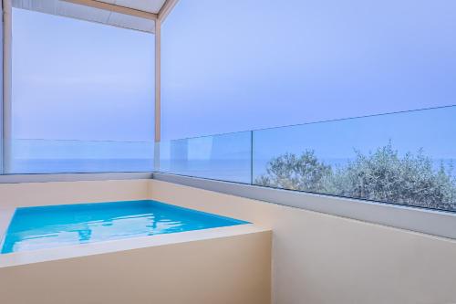 a bath tub in a room with a large window at Anasa Corfu in Benitses