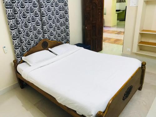 Bett in einem Zimmer mit weißem Bettlaken in der Unterkunft ECO VILLA in Puducherry
