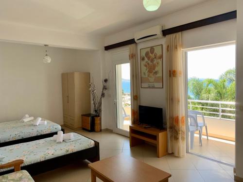 a room with two beds and a television and a balcony at Duka Apts in Sarandë