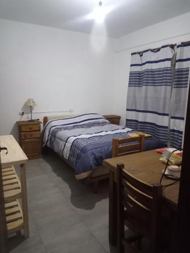 Schlafzimmer mit einem Bett, einem Tisch und einem Schreibtisch in der Unterkunft Hostal Tia Dora in San Salvador de Jujuy