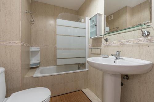 een badkamer met een wastafel, een toilet en een spiegel bij tuGuest Héroe Apartment in Málaga