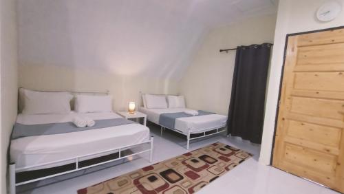 - une petite chambre avec 2 lits et une porte dans l'établissement Zainab Cottage, à Pasir Puteh