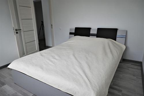 a bedroom with a bed with white sheets and two chairs at Bright and cozy apartment nr. 1 in Chişinău