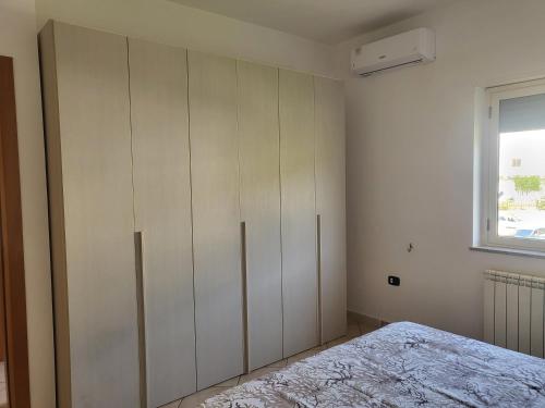 ein Schlafzimmer mit einem Bett und einem großen weißen Schrank in der Unterkunft San Silvestro House in Cariati