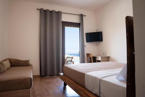 a bedroom with a bed and a couch and a window at DIPOLIS luxury apartments Syros in Episkopíon
