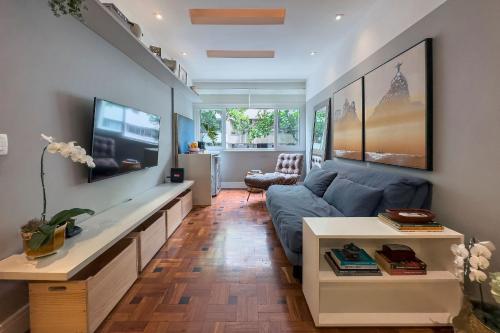 a living room with a blue couch and a flat screen tv at Prédio - El Paso - Acomodações estilosas do Leblon - por Casapē in Rio de Janeiro