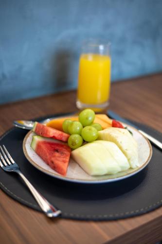 a plate of fruit on a table with a glass of orange juice at Ramada Hotel & Suites Campos Pelinca in Campos dos Goytacazes