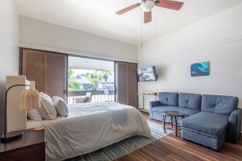 1 dormitorio con 1 cama y 1 sofá azul en Waiakea Villas 4329 condo, en Hilo