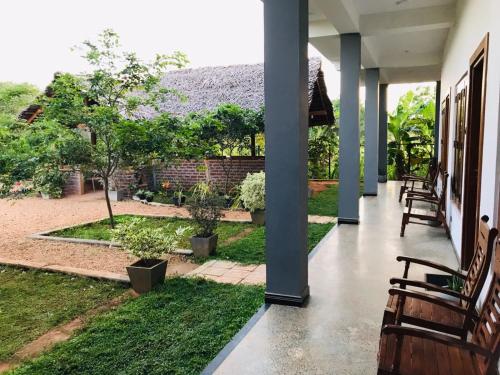 eine Veranda eines Hauses mit Stühlen und einem Garten in der Unterkunft Hotel Hanguk Villa in Dambulla
