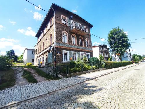 un edificio de ladrillo al lado de una calle en Apartamenty Anka Szczawno Zdrój, en Szczawno-Zdrój