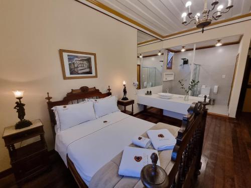 a bedroom with a bed and a bathroom with a sink at Teatro Hotel Boutique in Ouro Preto