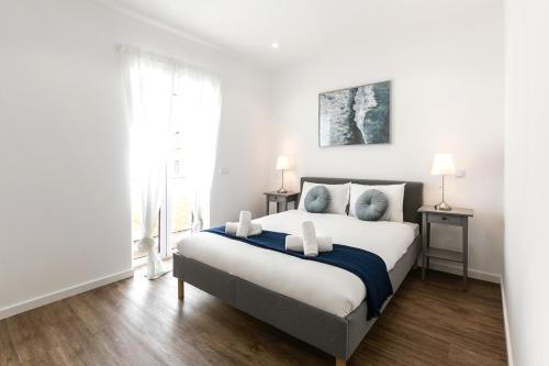 a white bedroom with a large bed and a window at O Sítio do Tomás in Nazaré