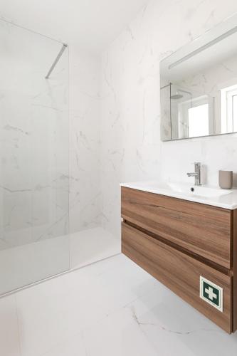 a white bathroom with a sink and a shower at O Sítio do Tomás in Nazaré