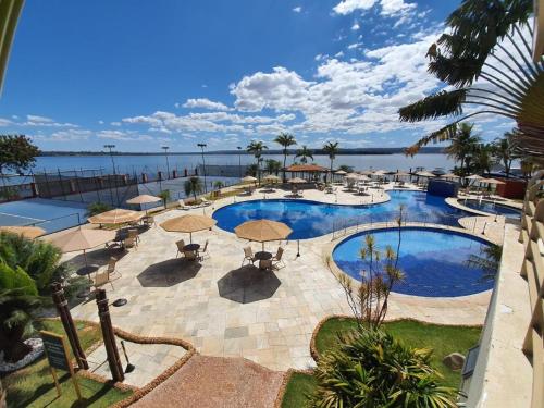 a large swimming pool with umbrellas and the water at Flat LakeSide -Vista para o lago C17 in Brasilia