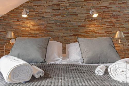 Cette chambre comprend un lit avec des oreillers et un mur en briques. dans l'établissement Les suites locarno, à Limoges