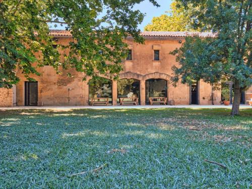 a building with a large yard with trees in front of it at La bambouseraie de sulauze in Miramas