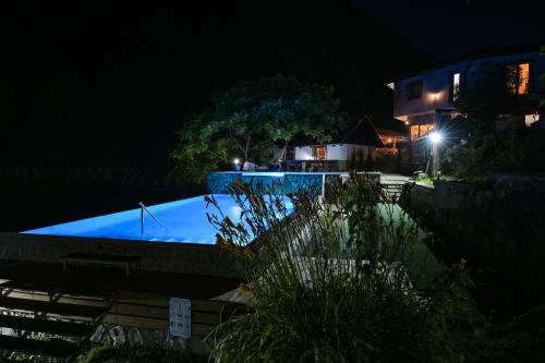 a swimming pool at night with a house in the background at Prenoćište Slapovi in Jajce