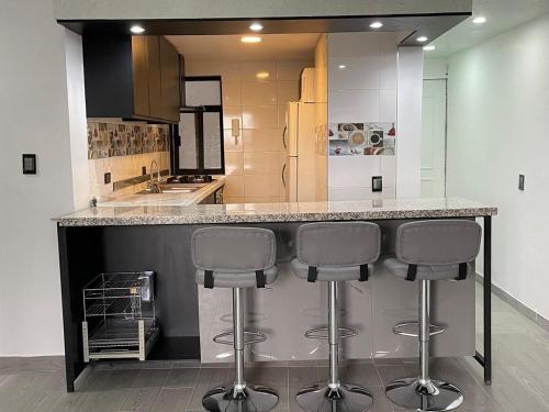 a kitchen with a counter with three bar stools at Perfecta Ubicación en Ciudad de México in Mexico City
