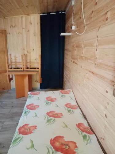 a bed in a room with a bedsheet with red flowers at Agroturystyka u Edwarda in Karwia