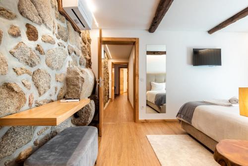 um quarto com duas camas e uma parede de pedra em Feel Discovery Casa da Pedra em Arouca