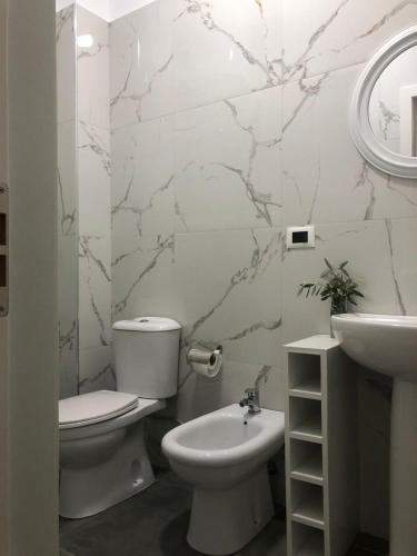 a white bathroom with a toilet and a sink at Ornela Apartments in Durrës