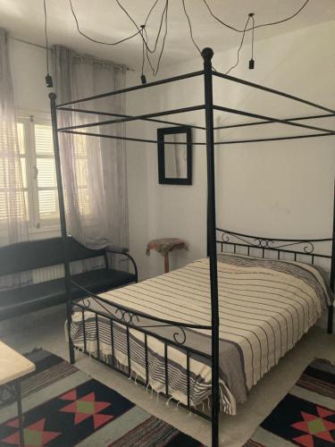拉馬薩的住宿－La Marsa Maison avec jardin, terrasse parking Wifi Illimité，一间卧室配有一张黑色天蓬床。
