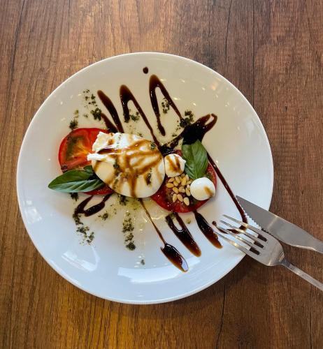 a white plate with food on a wooden table at Hotel AVENUE in Ravda