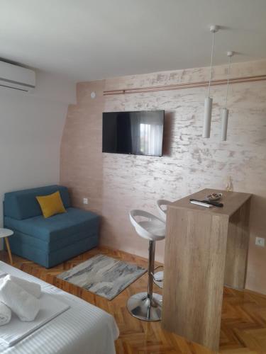 a bedroom with a bed and a blue couch and a tv at Holiday apartament three in Niš