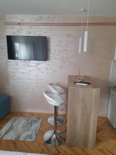 a room with a bar stool and a tv on a wall at Holiday apartament three in Niš
