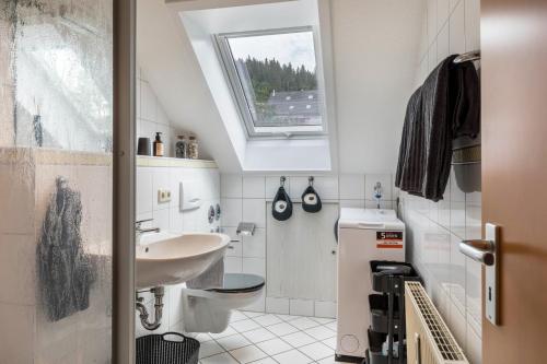 een badkamer met een wastafel, een toilet en een raam bij Weitblick in Breitnau