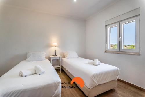 two beds in a room with a window at #179 Wide Backyard in Countryside in Albufeira