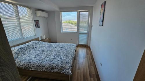 a bedroom with a bed and two windows at Kros Properties - Central in Varna City