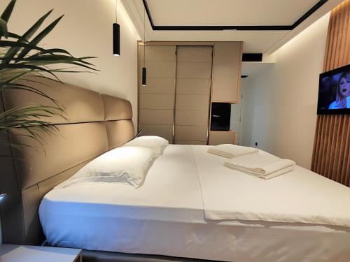 a bedroom with a large white bed and a tv at AMD Premium rooms Budva in Budva