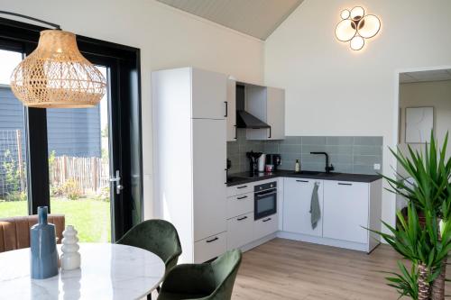 a kitchen with white cabinets and a table with chairs at 4 to 6 persons waterfront villa in Roelofarendsveen