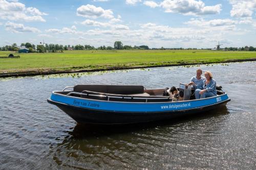 two people and a dog on a boat in the water at 4 to 6 persons waterfront villa in Roelofarendsveen