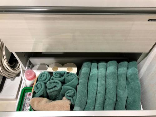 a drawer filled with green towels in a refrigerator at コンドミニアムHARU 那覇県庁前 202 in Naha