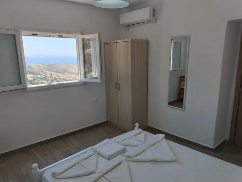 ein weißes Zimmer mit einem Bett und einem Fenster in der Unterkunft Silver View Aprovato in Apróvaton