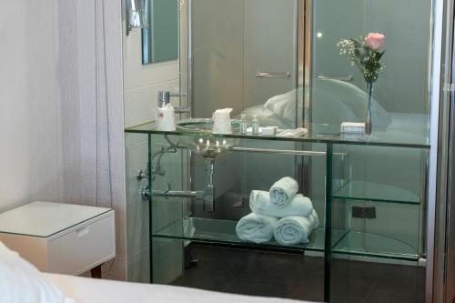 a bathroom with a glass cabinet with towels and a sink at Hotel Rural Spa Don Juan de Austria in Jarandilla de la Vera