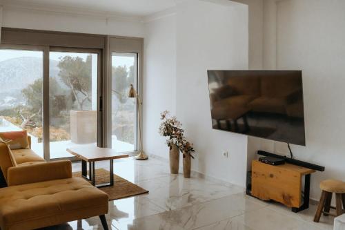a living room with a couch and a tv on a wall at Greek Sea Villas Kaki Thalassa 400m to the beach ,Athens in Keratea