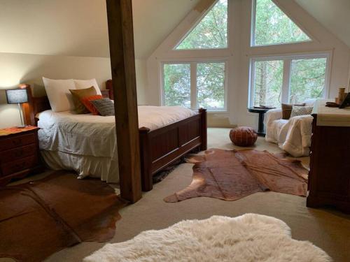 a bedroom with a bed and a large window at Algonquin Island 'Luxe' Cottage at the edge of the Park in South River