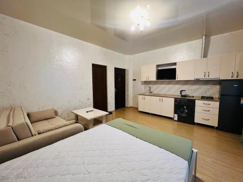a room with a bed and a couch and a kitchen at Apartments NITA in Batumi