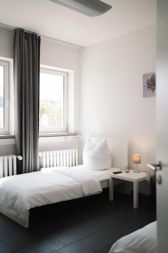 a white bedroom with two beds and a window at Ein, Zwei- oder Mehrbettzimmer/ Monteurszimmer in Leipzig